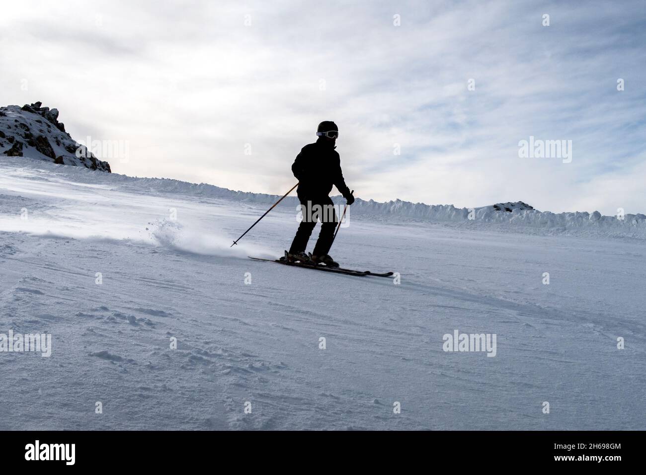 Skifahrer, die den verschneiten Hang hinunterfahren. Hintergrundbeleuchtung Stockfoto