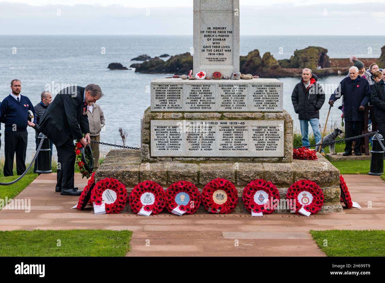 Dunbar, East Lothian, Schottland, Großbritannien, 14. November 2021. Gedenktag: Ein Gedenkgottesdienst an der Gedenkstätte und Kranzniederlegung des Krieges. Ein Mann legt an der Gedenkstätte einen Mohnkranz nieder Stockfoto