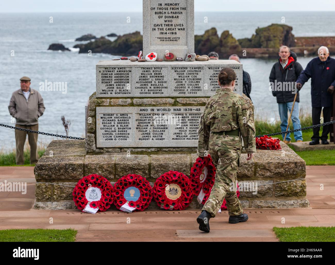 Dunbar, East Lothian, Schottland, Großbritannien, 14. November 2021. Gedenktag: Ein Gedenkgottesdienst an der Gedenkstätte und Kranzniederlegung mit einer Soldatin, die einen Mohnkranz legt Stockfoto