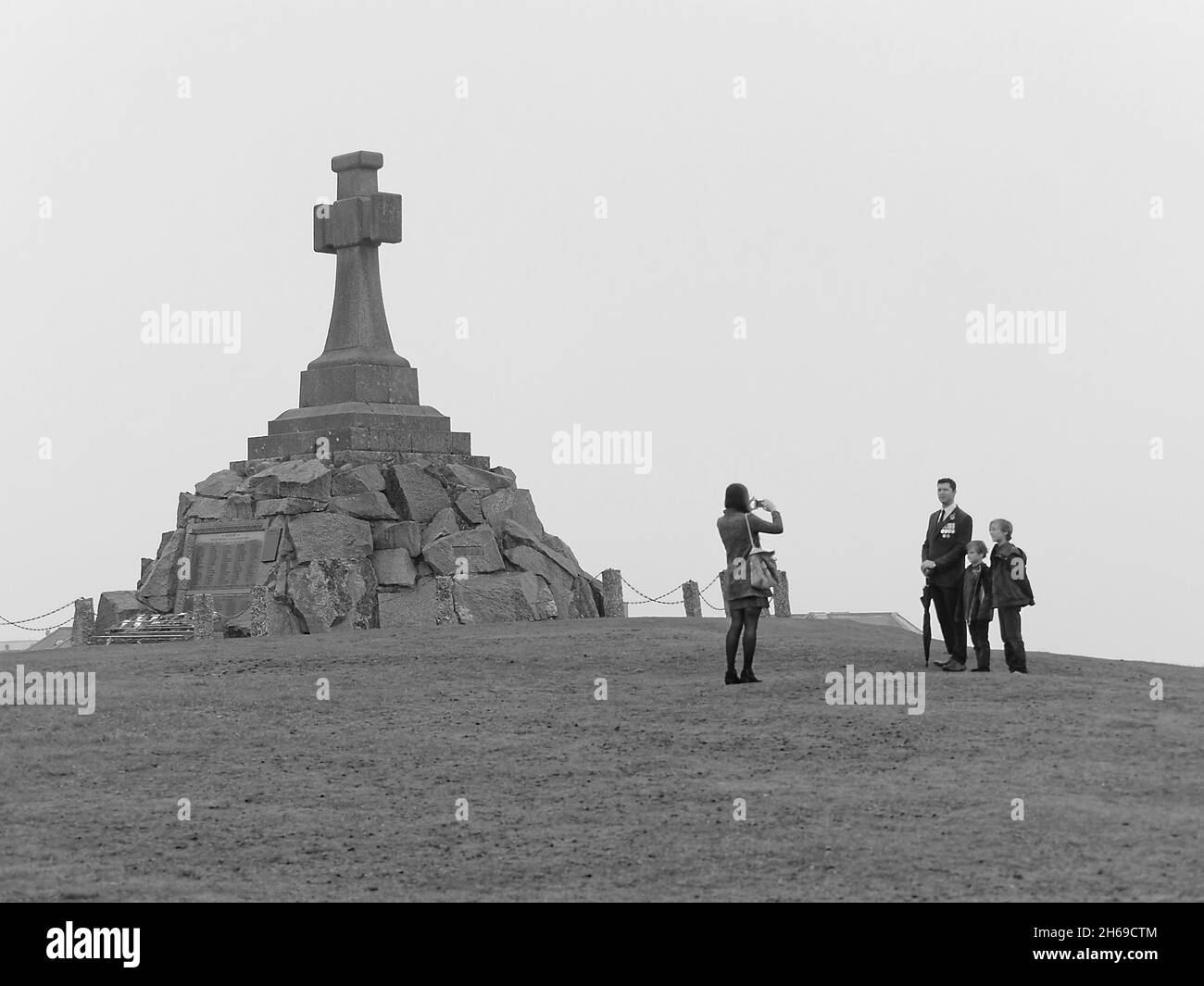 Newquay, Cornwall, Großbritannien. November 2021. Gurkha, Fallschirmjäger und NCOs der Royal Air Force marschieren Seite an Seite durch die Stadt Newquay zur St. Michaels Kirche zum jährlichen Gedenkgottesdienst. Vor dem zweiminütigen Schweigen besucht ein ehemaliger Dienstoffizier mit seiner Familie das Bürgerkriegserdenkmal der Stadt. Eine einsame Figur mit einem Regenschirm respektiert schweigend die Gefallenen an der Gedenkstätte. 14. November, 2021 Quelle: Robert Taylor/Alamy Live News Stockfoto