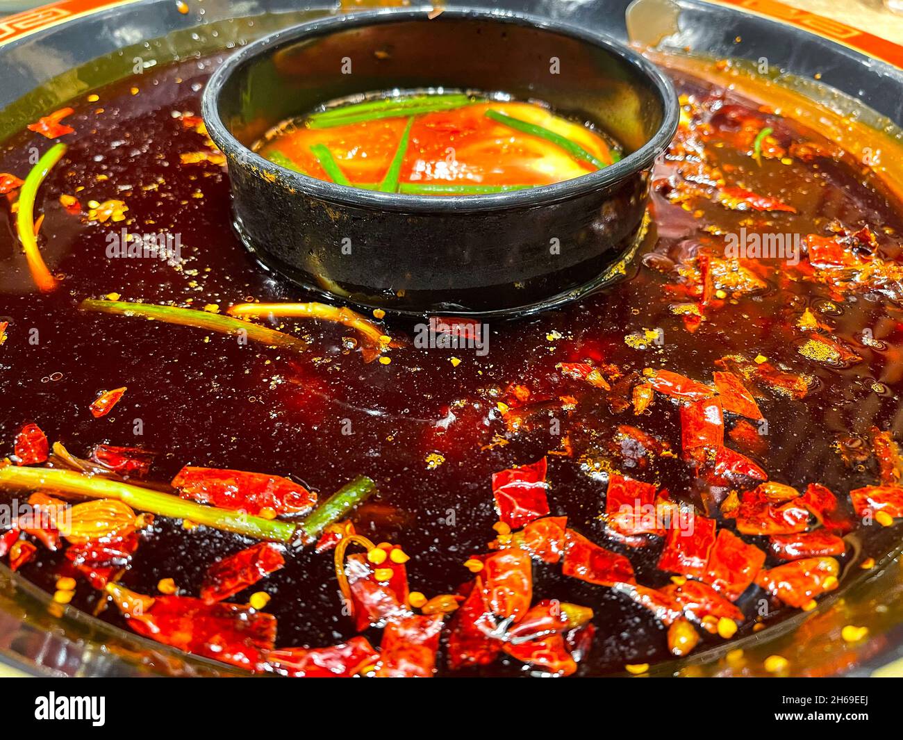 Rote, scharf gewürzte Chilischoten schwimmen im weltberühmten Sichuan Hotpot Stockfoto