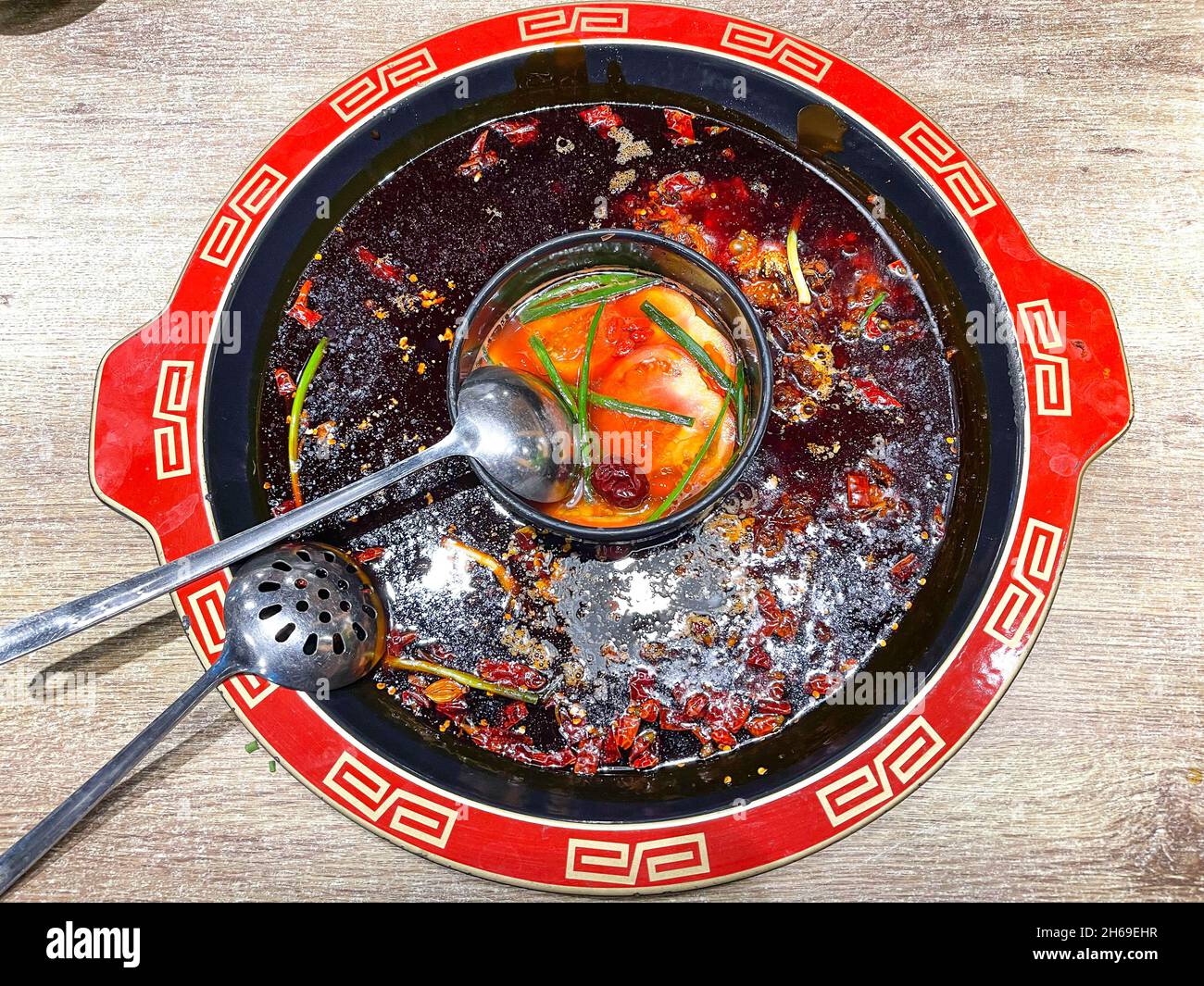 Sichuan Hotpot mit würzigen Chilischoten auf der Außenseite und Tomatensuppe auf der Innenseite Stockfoto