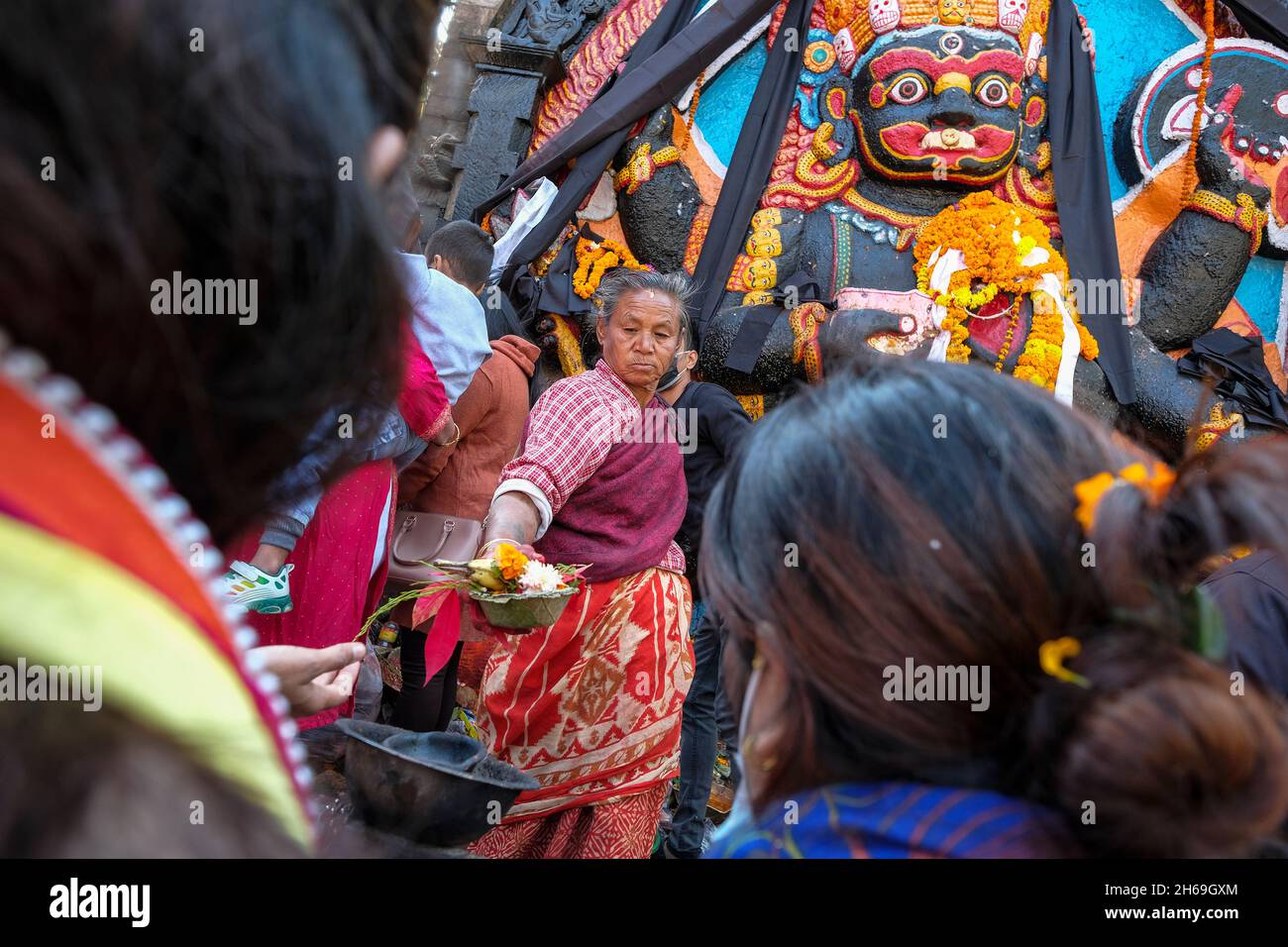 Kathmandu, Nepal - 2021. November: Pilger, die am 13. November 2021 in Kathmandu auf dem Durbar-Platz vor der Figur des Kala Bhairab Opfergaben, Stockfoto