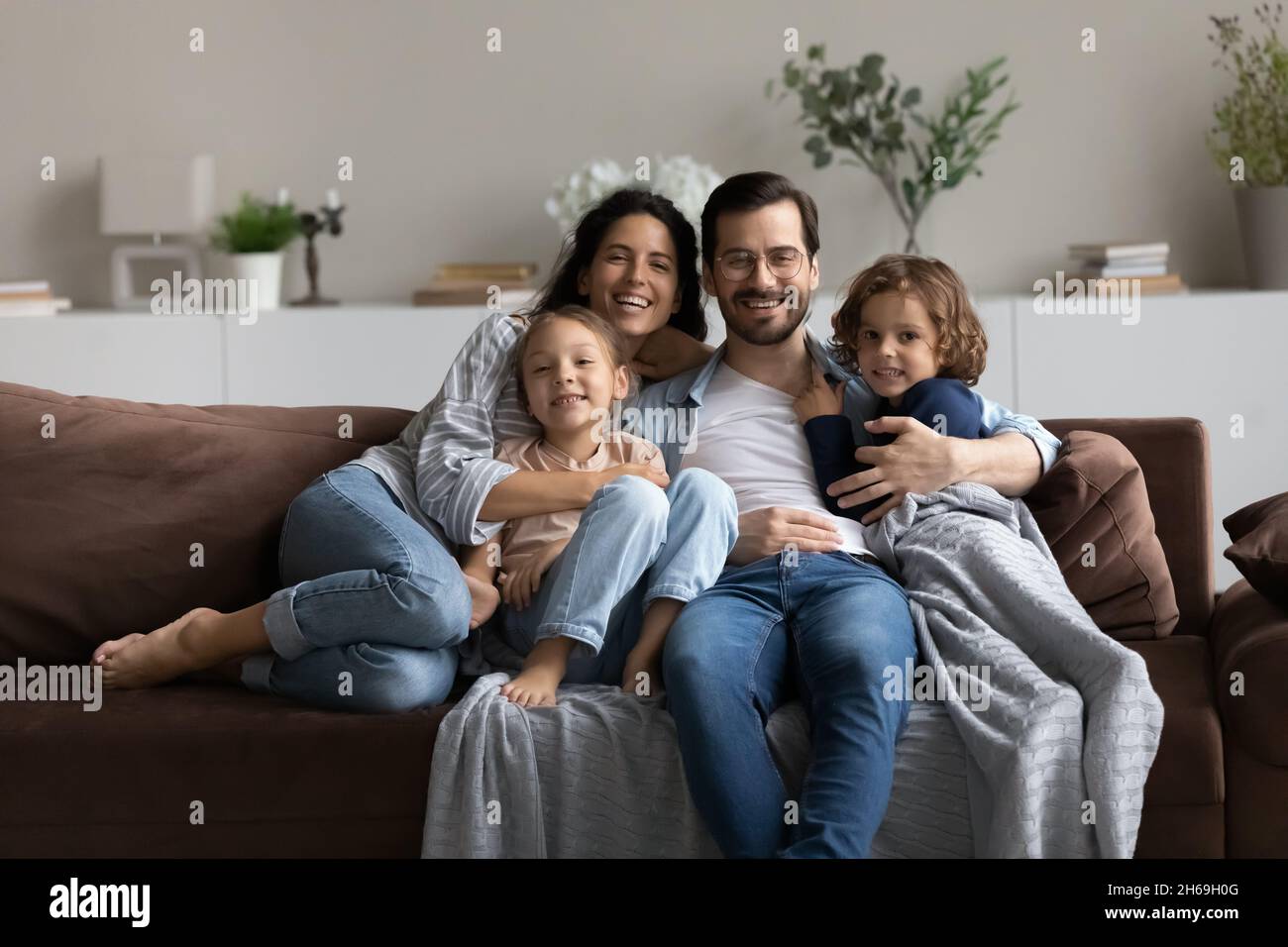 Porträt einer glücklichen Familie mit zwei Kindern, die auf der Couch sitzen Stockfoto