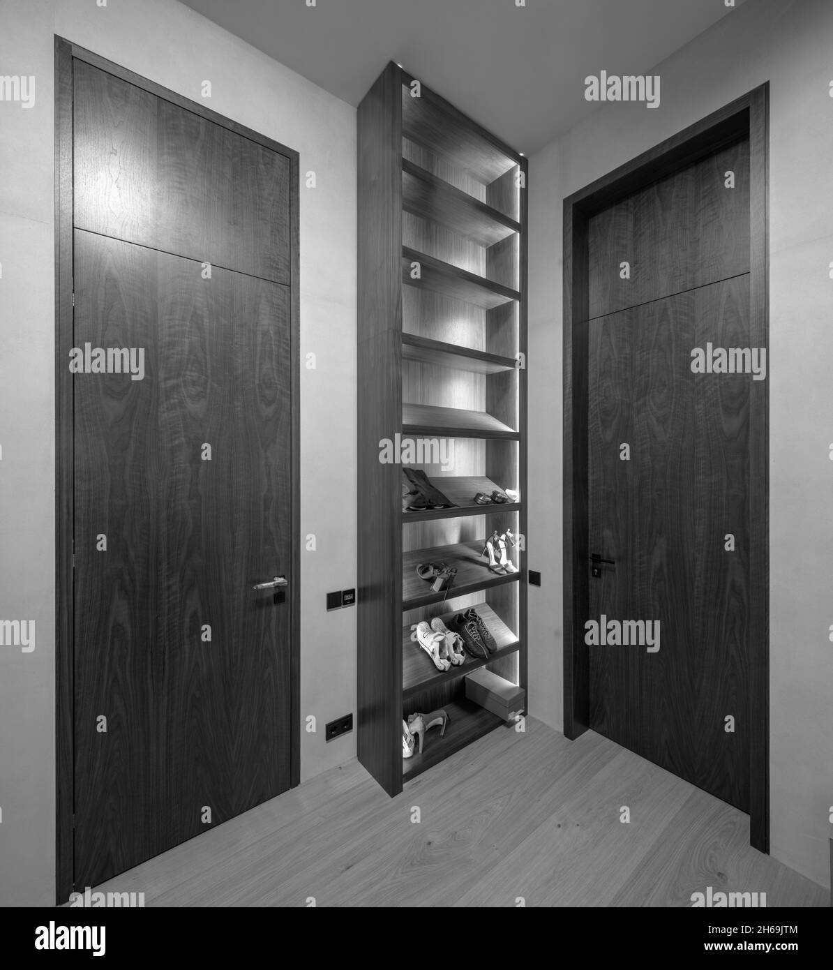 Modernes Interieur der Luxus-Wohnung. Beleuchtete Regale für Schuhe. Holztüren. Schwarz und Weiß. Stockfoto