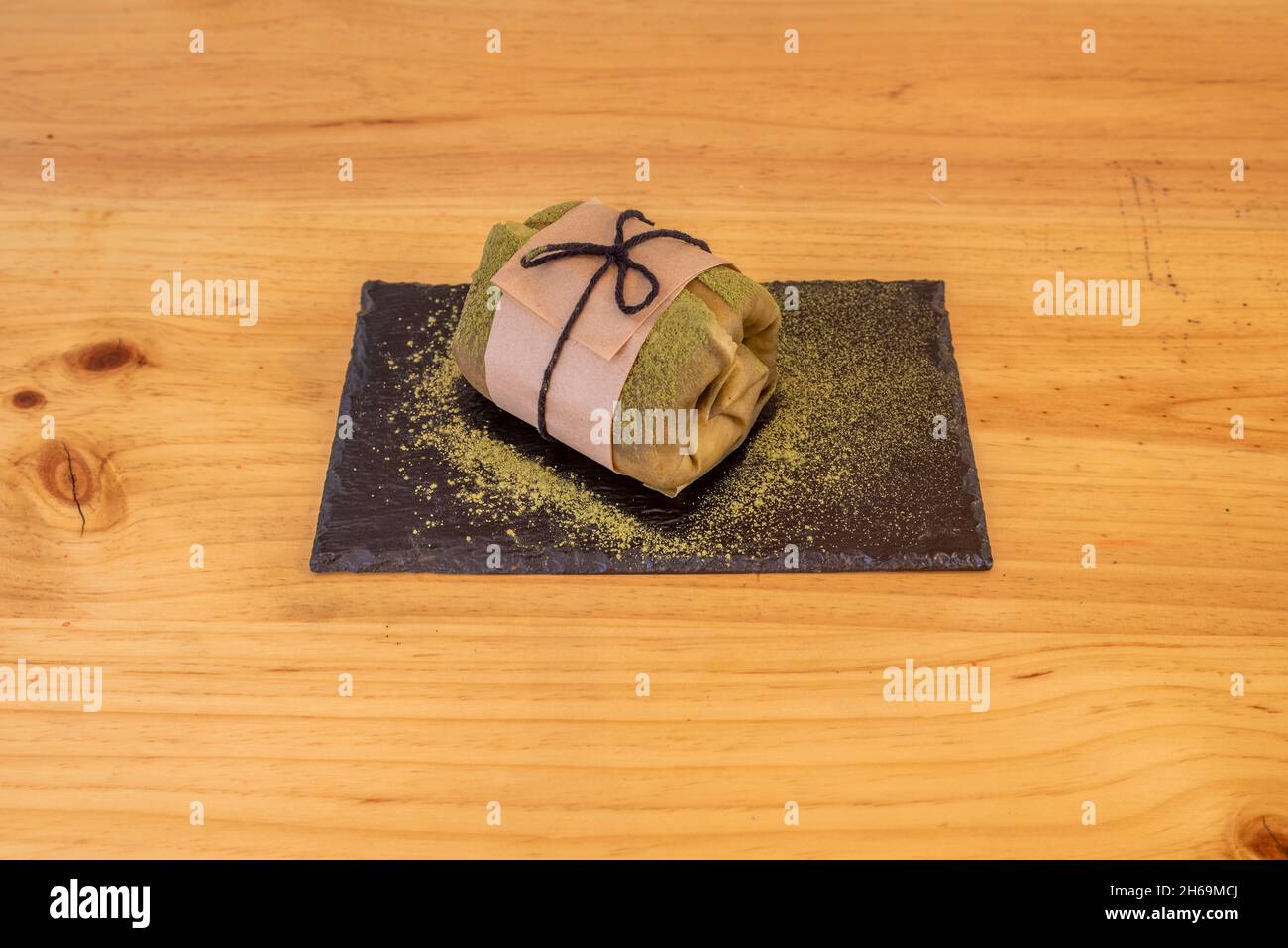 Crepe Roll gefüllt mit Schlagsahne und bestreut mit Matcha-Tee Stockfoto