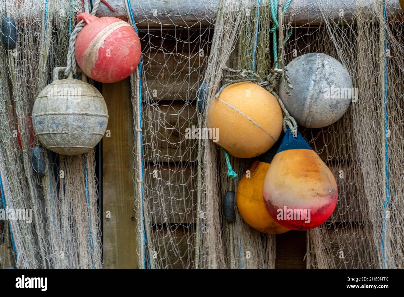 Farbenfrohe Fischschaufeln und Fischernetze hängen zum Trocknen an den Seiten einer alten hölzernen Strandhütte in der Steephill-Bucht bei ventnor auf der Insel wight. Stockfoto