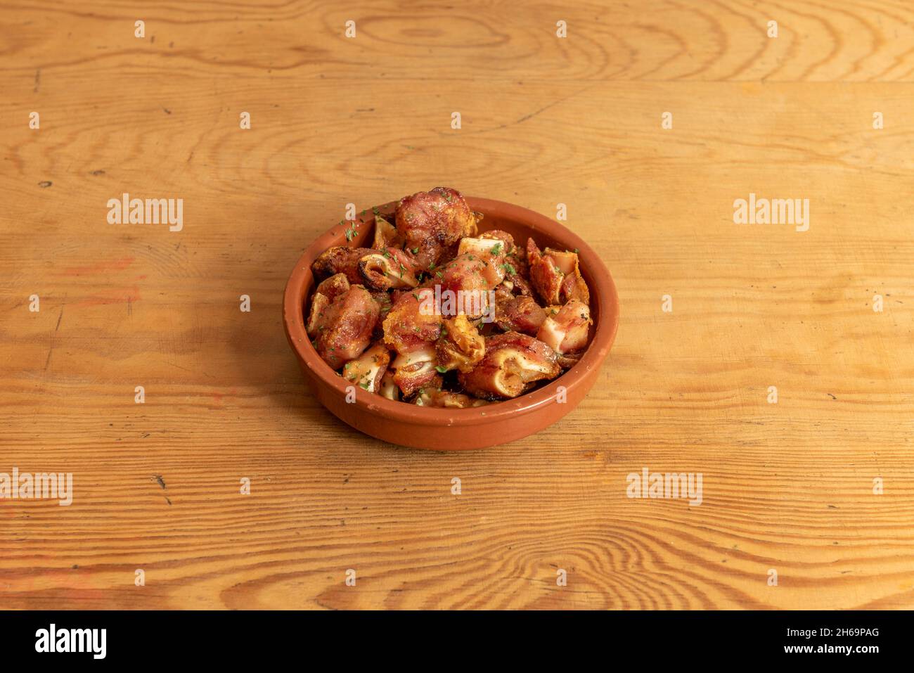 Beliebte spanische Tapas mit mariniertem Schweineohr vom Grill in einem Tontopf Stockfoto
