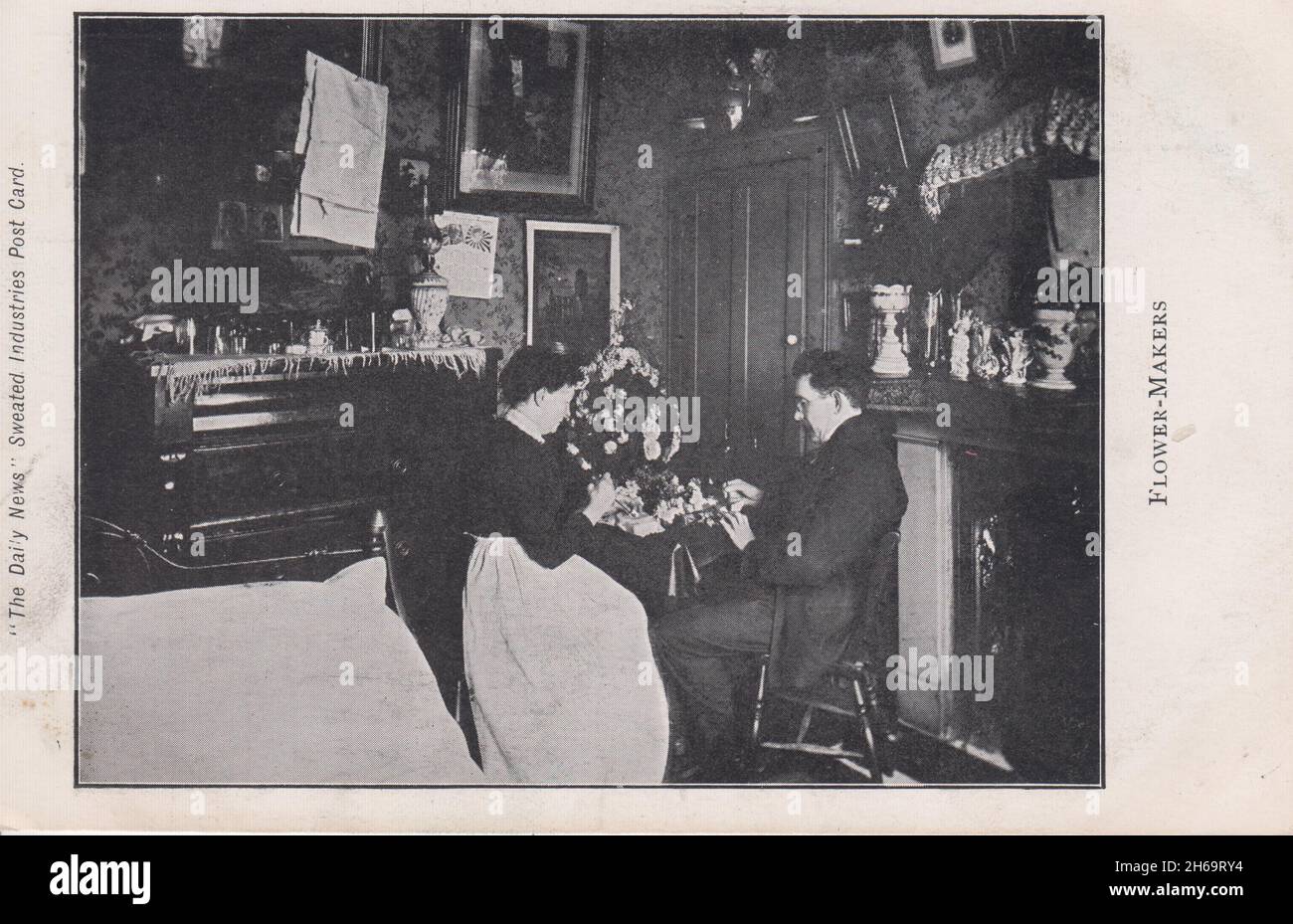 Blumenmacher (ein Mann und eine Frau), die in ihrem Haus gezeigt werden, um Artikel zum Verkauf zu machen. Um sie herum sind Gegenstände aus dem Haushalt zu sehen, darunter Bilder, Ornamente, eine Linie mit Leinen, die daran hängt, und was das Kissen eines Bettes im Vordergrund sein könnte. Dies ist eines von einer Serie von Bildern von Heimarbeitern, die als Postkarten von „The Daily News“ veröffentlicht wurden, um ausbeuterische „geschwemmte Geschäfte“ im Jahr 1906 im Rahmen der Kampagne der Zeitung zur Einführung eines Mindestlohns hervorzuheben Stockfoto
