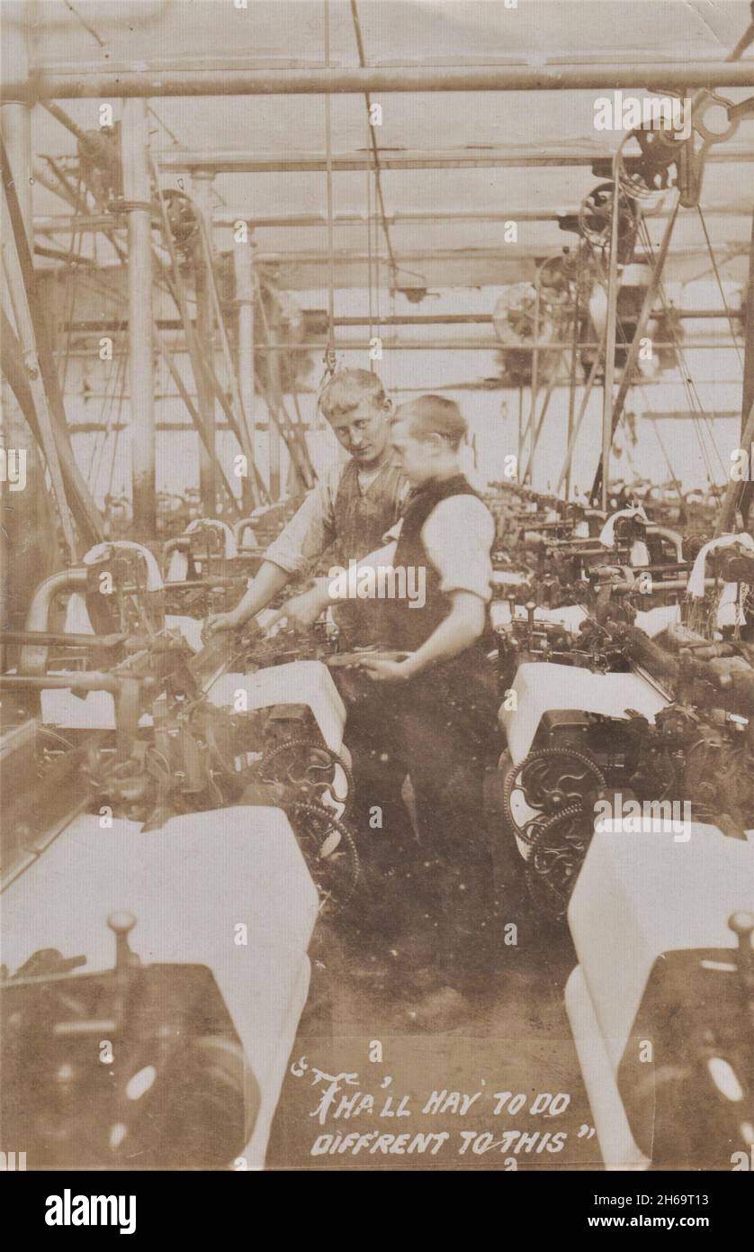 Baumwollfabrik Lancashire: Kleiner Junge, der sich zur Arbeit an einer Maschine lehnte und von seinem Chef (einem älteren Jugendlichen) getagt wurde, Anfang des 20. Jahrhunderts Stockfoto