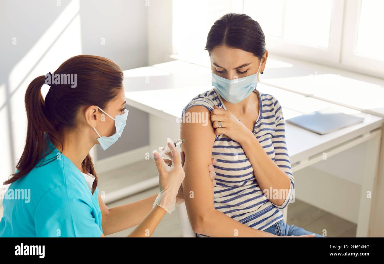 Arzt impfen weibliche Patienten im Gesichtsmast Stockfoto
