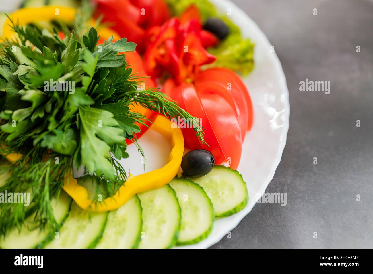 Verschiedene frische Gemüse auf einem Teller.Gericht aus Gurken, Paprika, Tomaten und Basilikum mit Petersilie und Gurke Stockfoto
