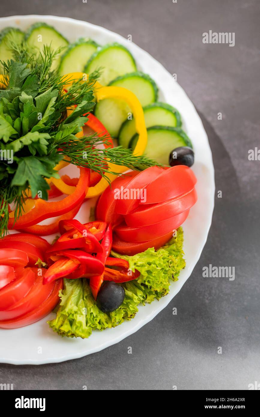 Verschiedene frische Gemüse auf einem Teller.Gericht aus Gurken, Paprika, Tomaten und Basilikum mit Petersilie und Gurke Stockfoto