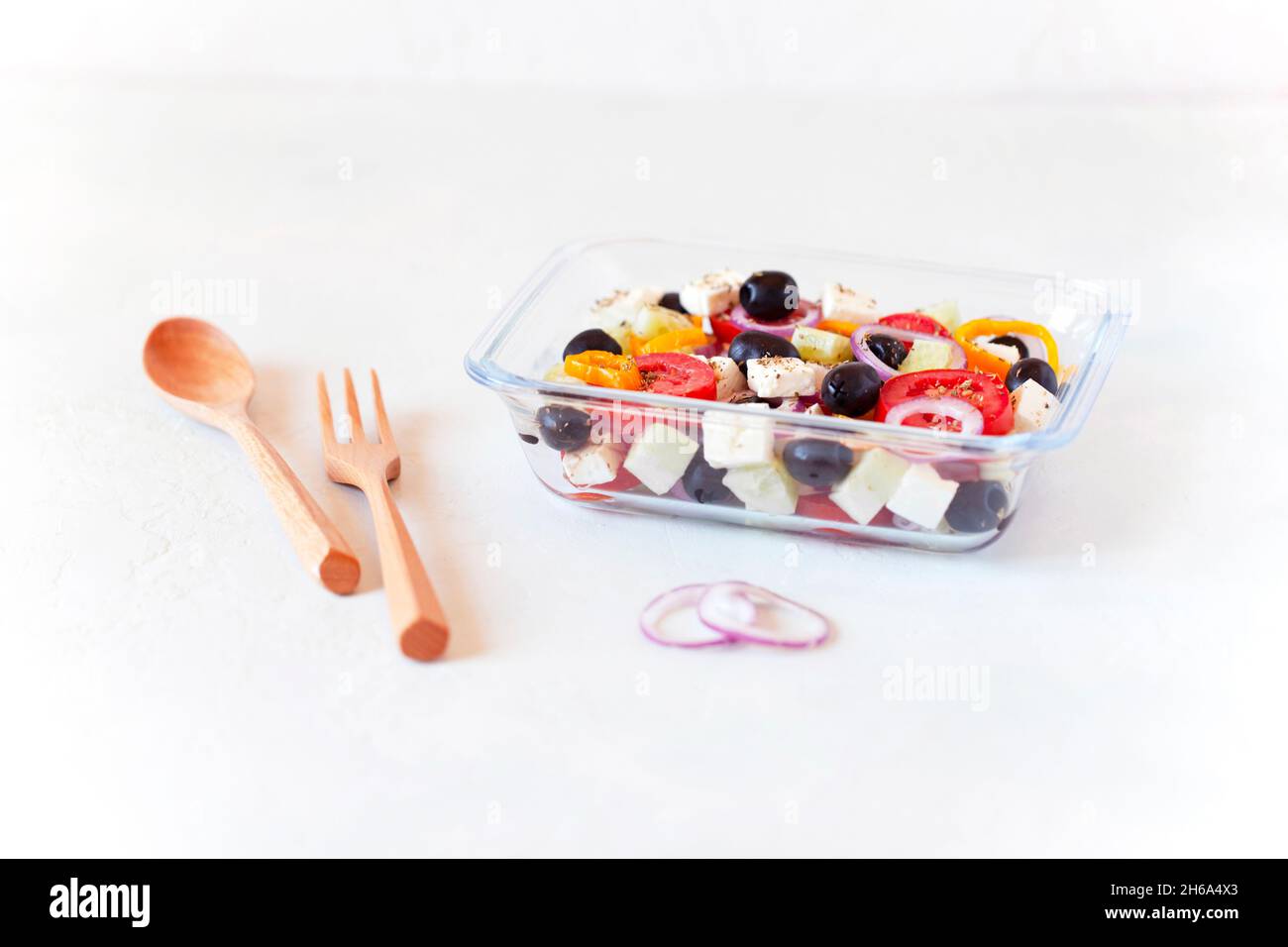 Lunchbox mit griechischem Salat, wiederverwendbarem Glasbehälter, Holzbesteck, auf weißem Hintergrund, Seitenansicht Stockfoto