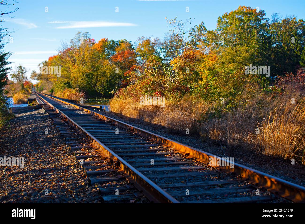 Eisenbahnstrecken, die an einem sonnigen Herbsttag im Thompson Park, Monroe, New Jersey, durch einen kleinen See führen - 01 Stockfoto