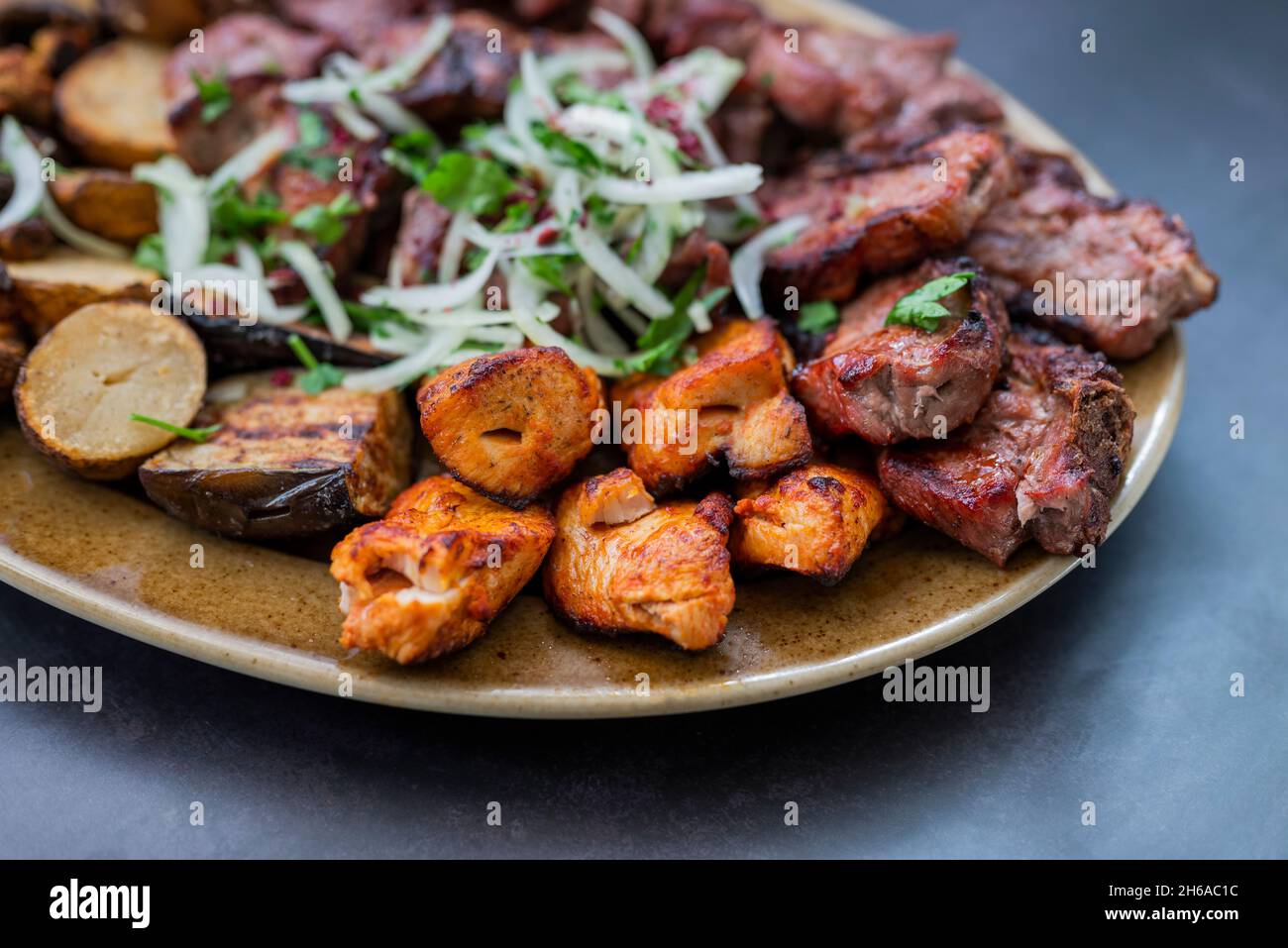 Fleischstücke Grillen gegrilltes Schweinefleisch und Rind und Huhn auf einem Teller mit Zwiebeln in einem Restaurant Stockfoto