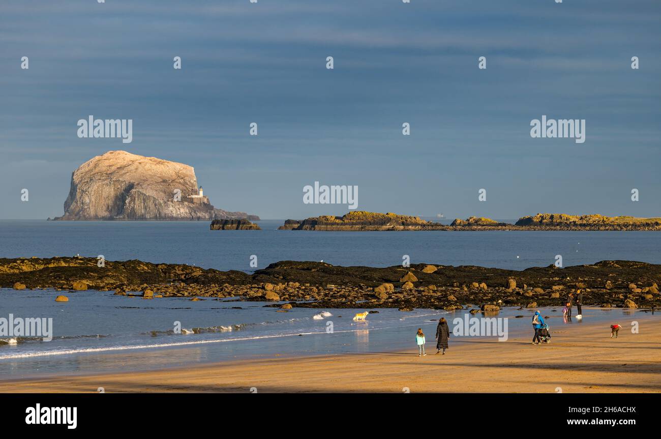 Menschen, die am Sandstrand von Milsey Bay mit Bass Rock am Horizont, North Berwick, East Lothian, Schottland, Großbritannien, spazieren gehen Stockfoto