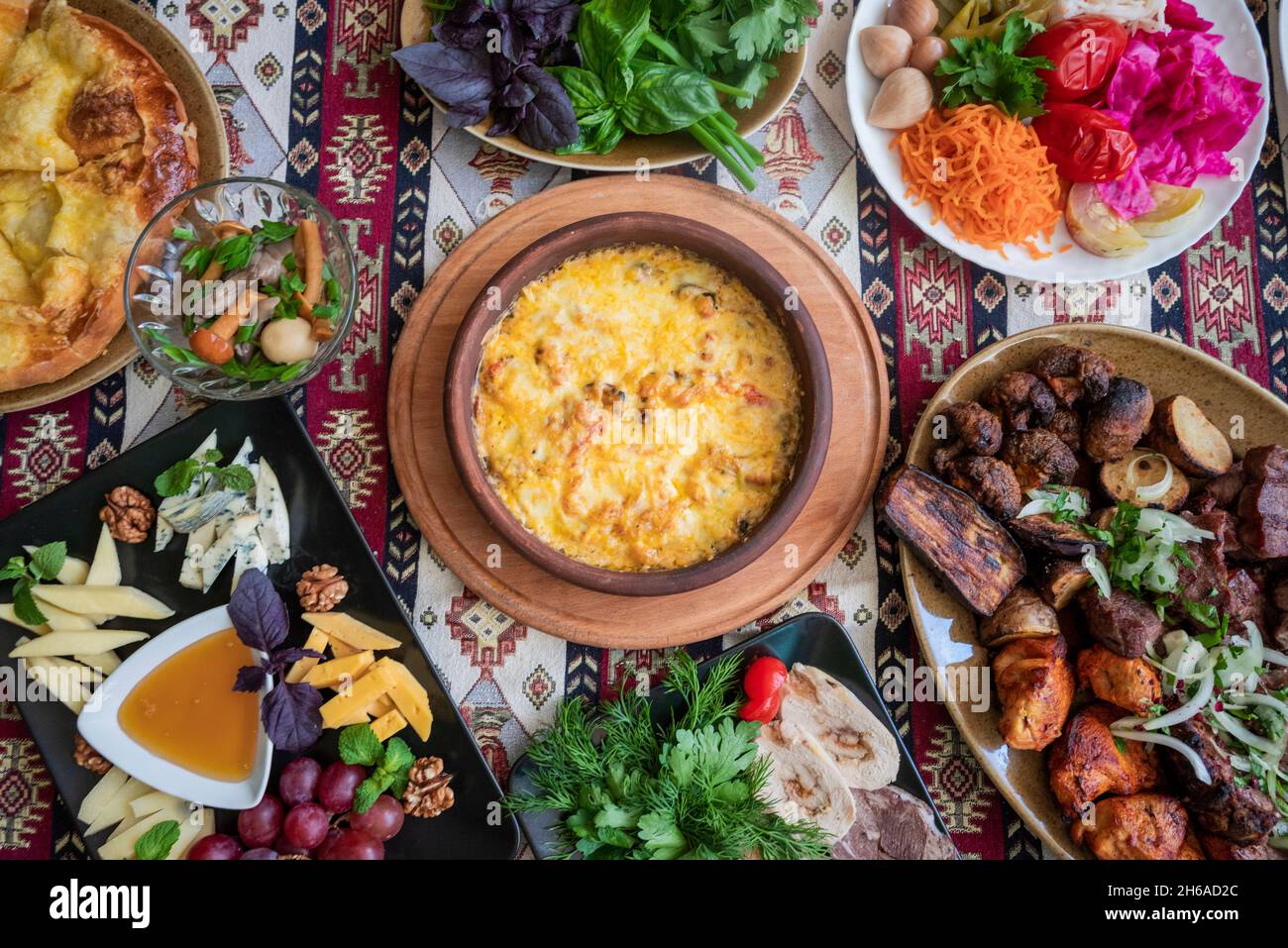 georgische und aserbaidschanische nationale Küche Suluguni Gerichte gebackenen adjarischen khachapuri, Pilze und Gemüse und Kräuter mit einem Teller mit verschiedenen Käsesorten Stockfoto