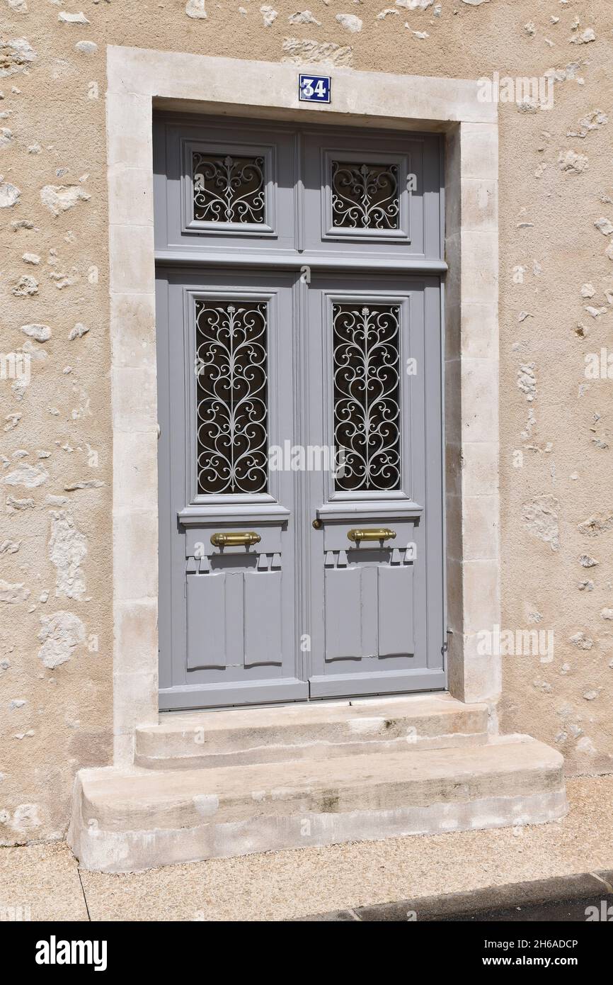 Die Eingangstür eines Stadthauses mit Doppelfassade in Montmorillon, Frankreich, typischer Stil der Mitte C19, Doppeltüren, schwere Zierleisten, Fenster mit Metallgrillen Stockfoto