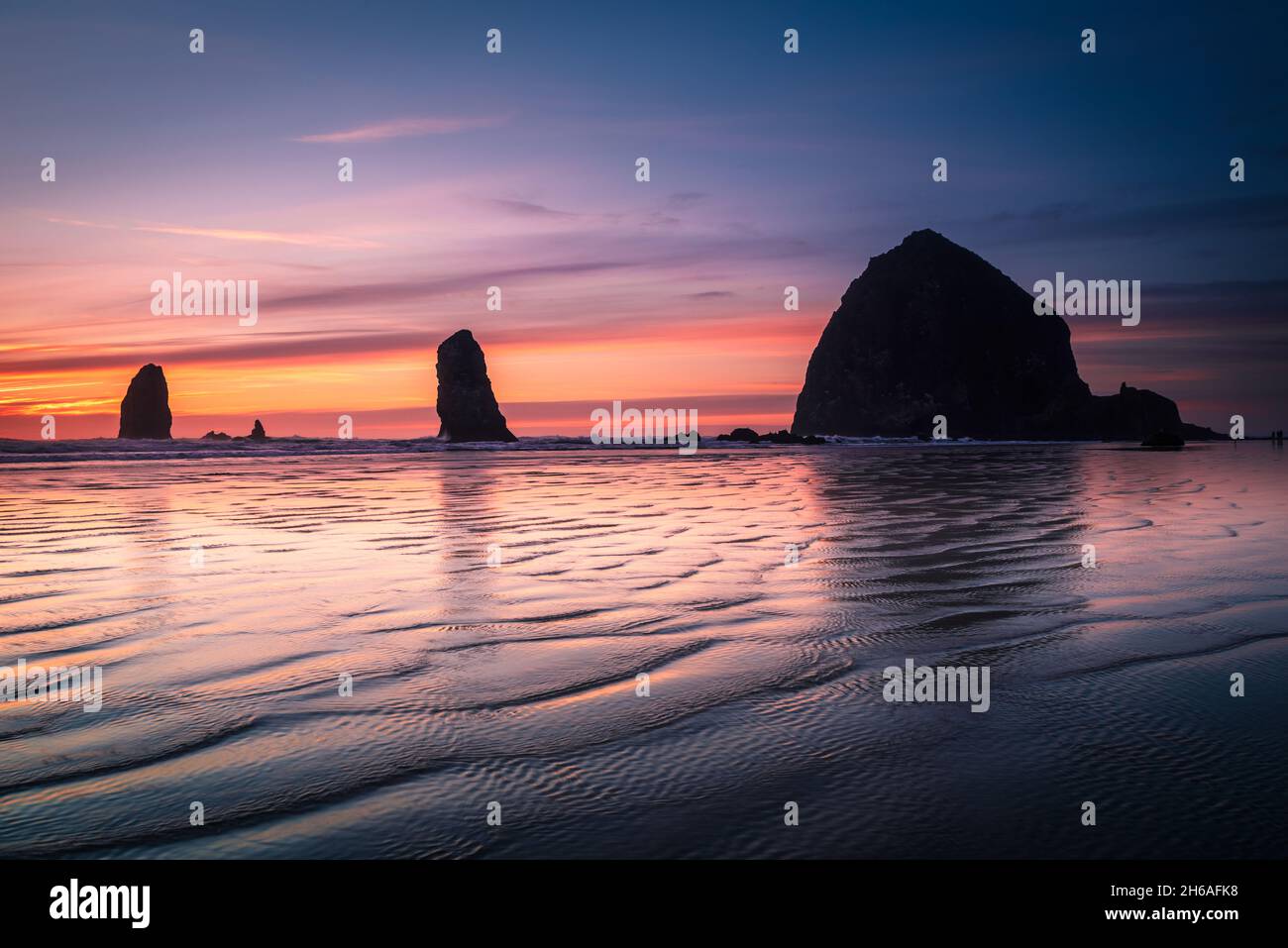 Wellen und Sonnenuntergänge vor dem Heuhaufen am Strand von Cannon Stockfoto