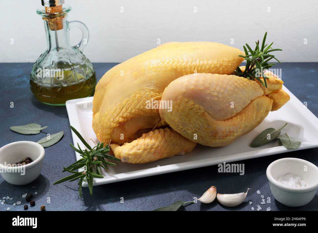 Ganz rohes Huhn mit Gewürzen und Kräutern isoliert auf grauem Hintergrund. Nahaufnahme. Stockfoto