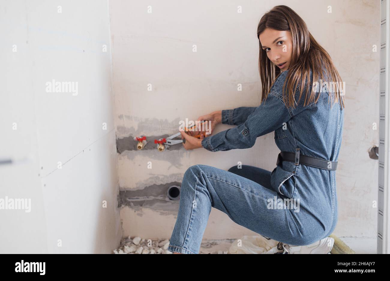 Eine junge Frau macht Wohnungsrenovierungen allein. Apartment Renovierungskonzept. Starke unabhängige Frau Stockfoto