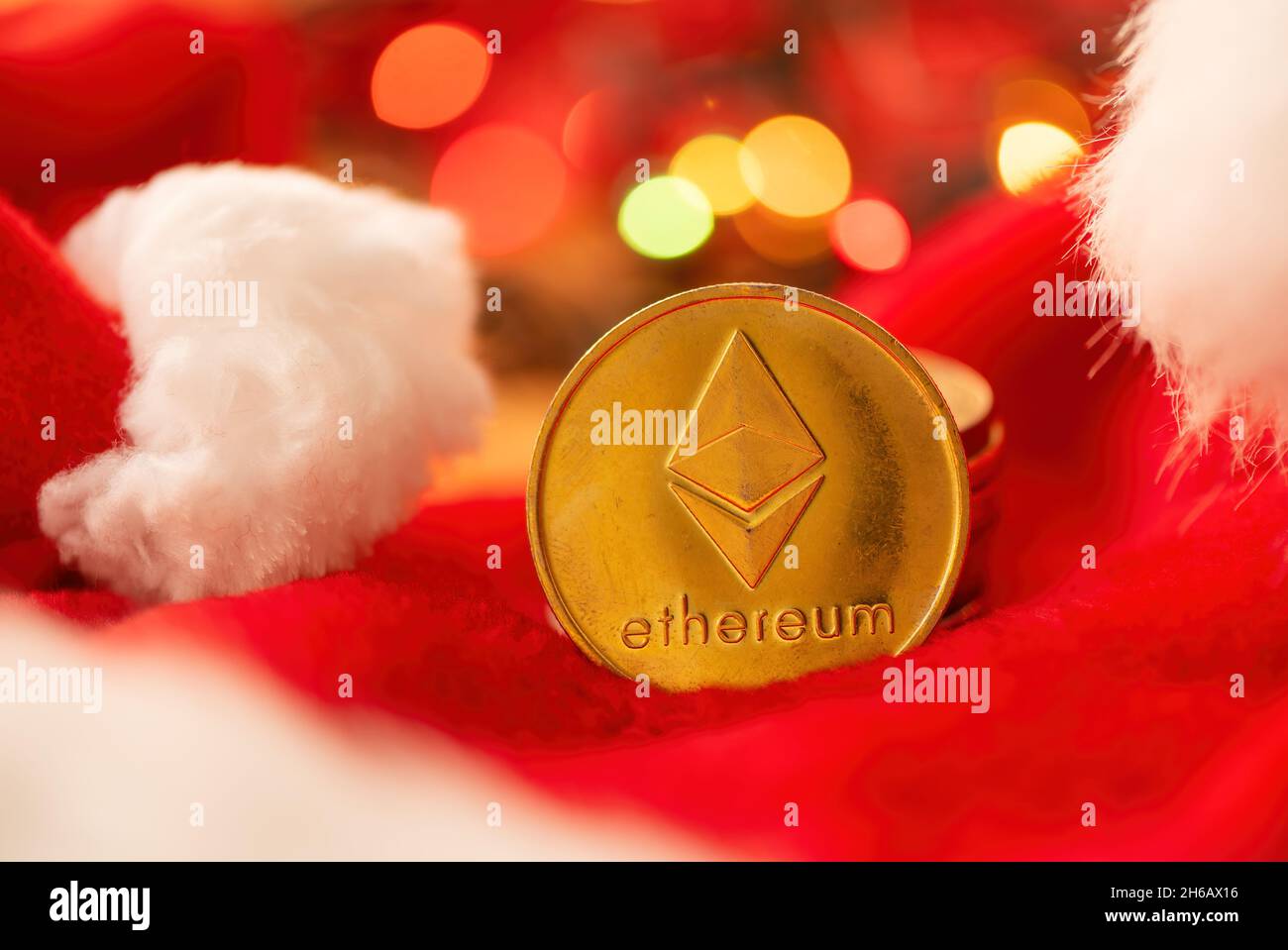 Ethereum-Münze mit Weihnachtsfesttagsdekoration, Münzstapel und Weihnachtsmannhut mit festlichem Fadenlicht im Bokeh-Hintergrund, selektiver Fokus Stockfoto