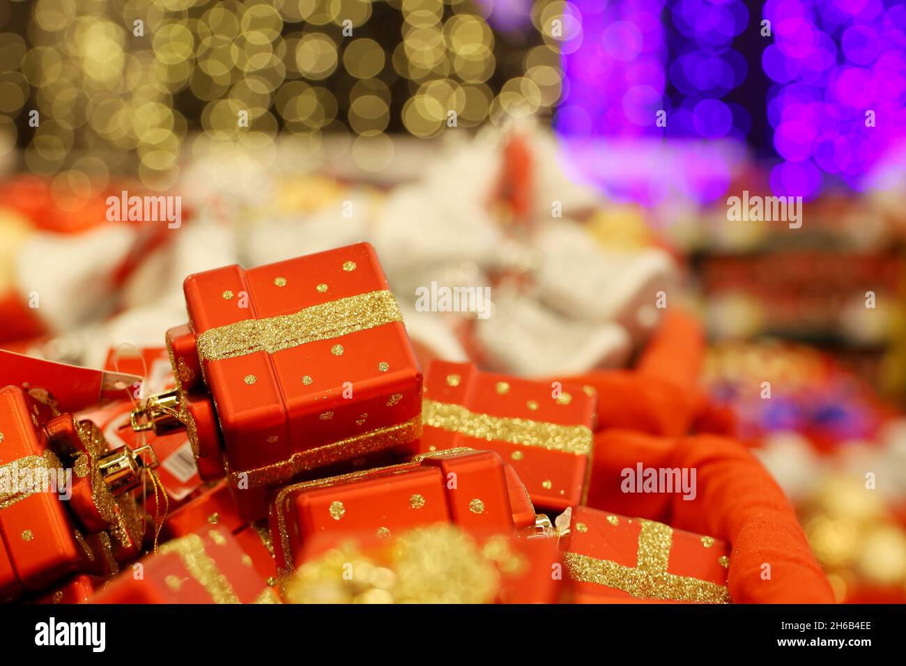 Weihnachtsspielzeug, rote Geschenkschachteln in einem Korb. Neujahrsdekoration in einem Geschäft auf unscharfem festlichem Hintergrund Stockfoto