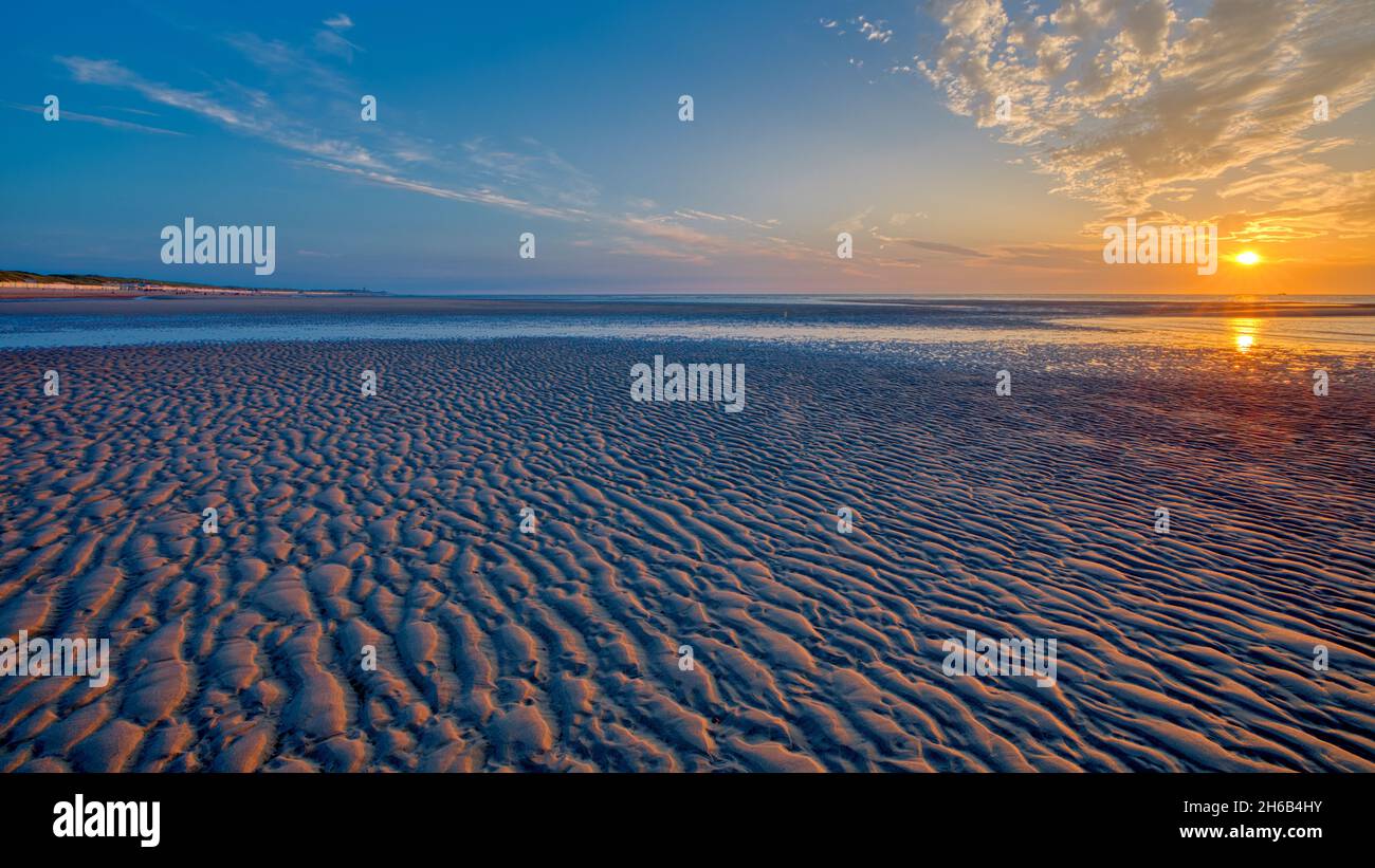 Sonnenuntergang am Strand von Zeeland (Niederlande). Die Sonne ist schön, wenn Schleierwolken am Himmel leuchten. Stockfoto