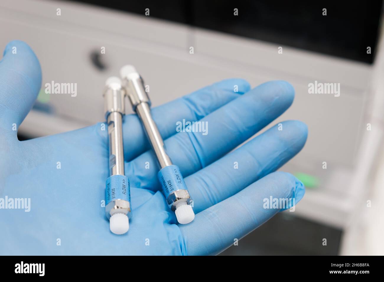 Kleine HPLC-Säulen mit 50 mm Durchmesser zur Trennung von Verbindungen im Labor Hand in Gummihandschuh. Schnelle Hochleistungs-Flüssigchromatographie-Analyse im chemischen und mikrobiologischen Labor. Klinische, toxikologische und forensische Analysen. Stockfoto