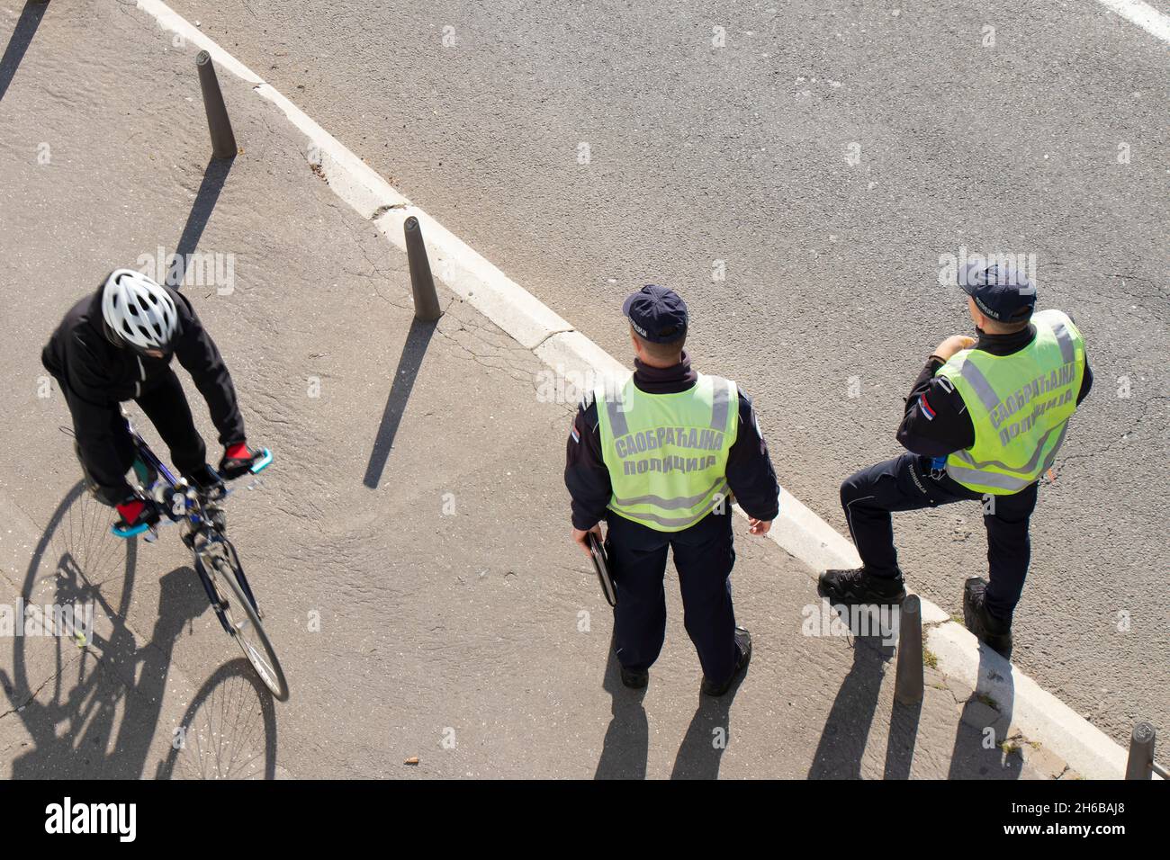 Belgrad, Serbien - 25. Oktober 2021: Zwei Verkehrspolizisten im Dienst auf der Stadtstraße und ein Radfahrer, der in Bewegung vorbeifährt, verwackelt, Rückansicht aus dem hohen Winkel Stockfoto