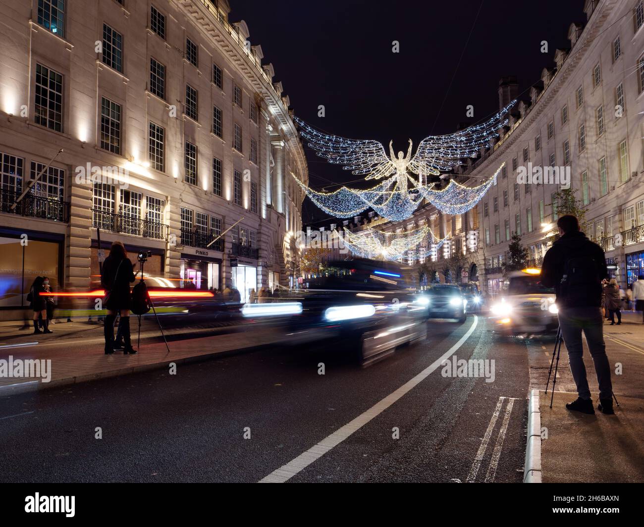 Weihnachtliche Stimmung in der Regent Street bei Nacht, wenn der Verkehr zugeht und Fotografen versuchen, die Szene einzufangen. Stockfoto