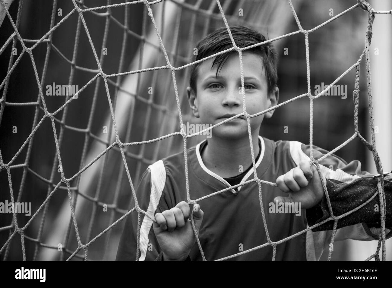 Porträt eines Jungen im Teenageralter in der Nähe eines Tores auf dem Fußballfeld. Schwarzweiß-Foto. Stockfoto