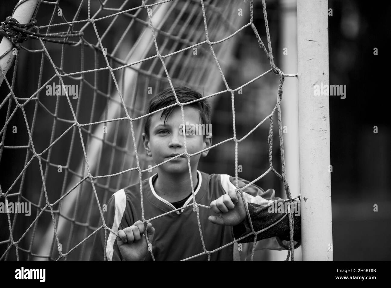 Ein Teenager-Jungen-Portrait in der Nähe des Tores auf dem Fußballfeld. Schwarzweiß-Foto. Stockfoto