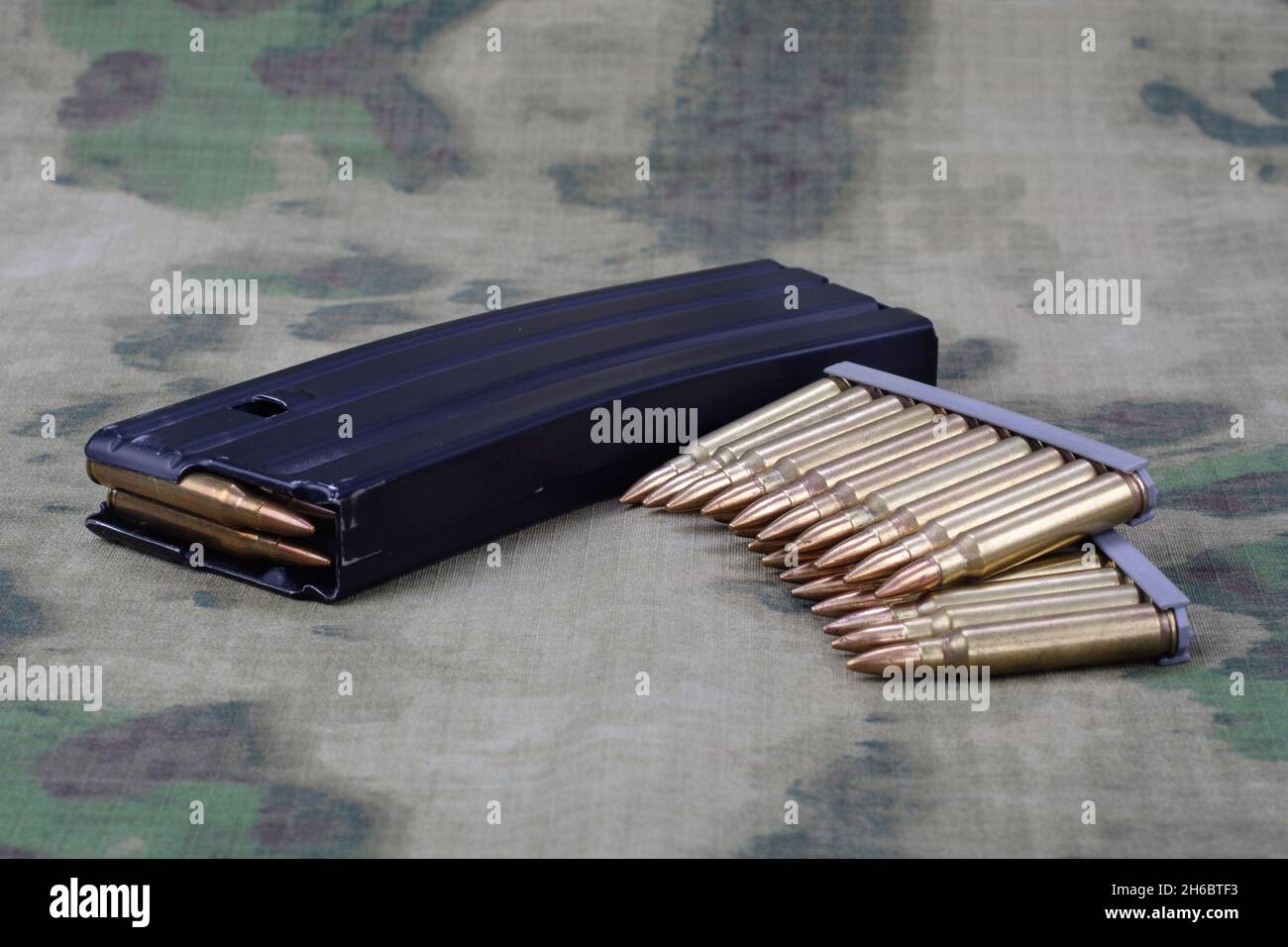 5.56mm-Munitionskugel mit Vollmetallmantel und Magazin an Camouflage uniform Hintergrund Stockfoto