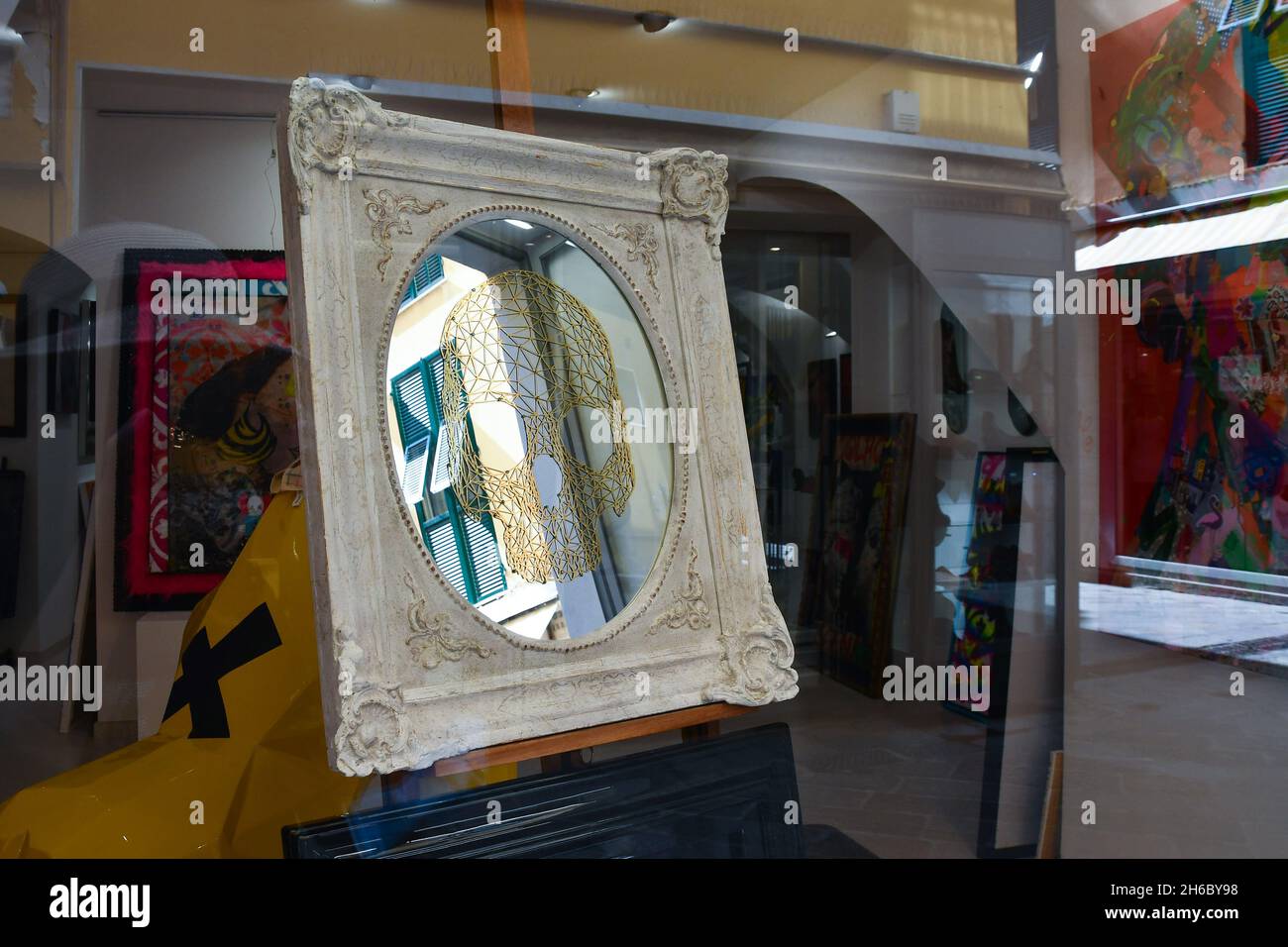 Ein künstlerischer Spiegel, der im Fenster der Kunstgalerie Arte è Kaos im historischen Zentrum von Alassio, Savona, Ligurien, Italien, ausgestellt ist Stockfoto