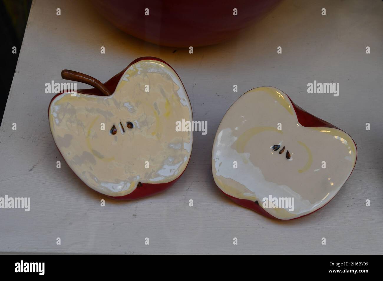 Nahaufnahme von Keramikskulpturen, die einen von Nadia Allario in zwei Hälften geschnittenen Apfel darstellen, im Schaufenster der Kunstgalerie Arte è Kaos, Alassio, Savona Stockfoto