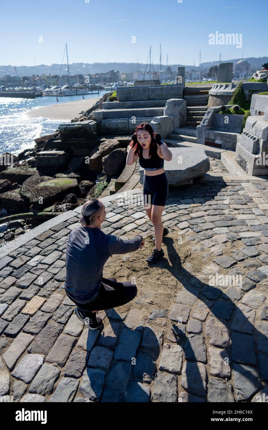 Junge asiatische Frau nimmt an der ersten MMA-Trainingseinheit mit Personal Trainer Teil Stockfoto