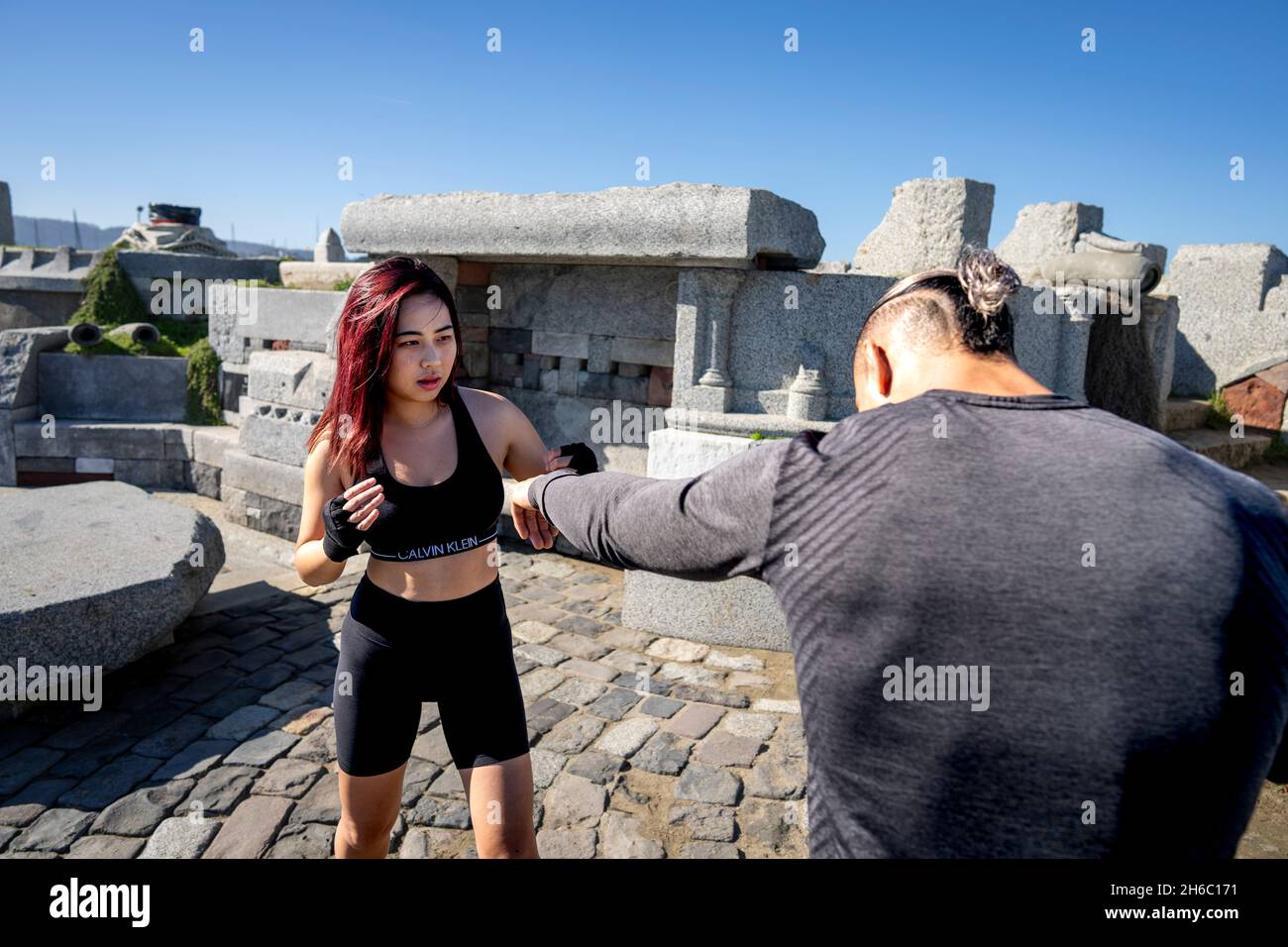 Junge asiatische Frau nimmt an der ersten MMA-Trainingseinheit mit Personal Trainer Teil Stockfoto