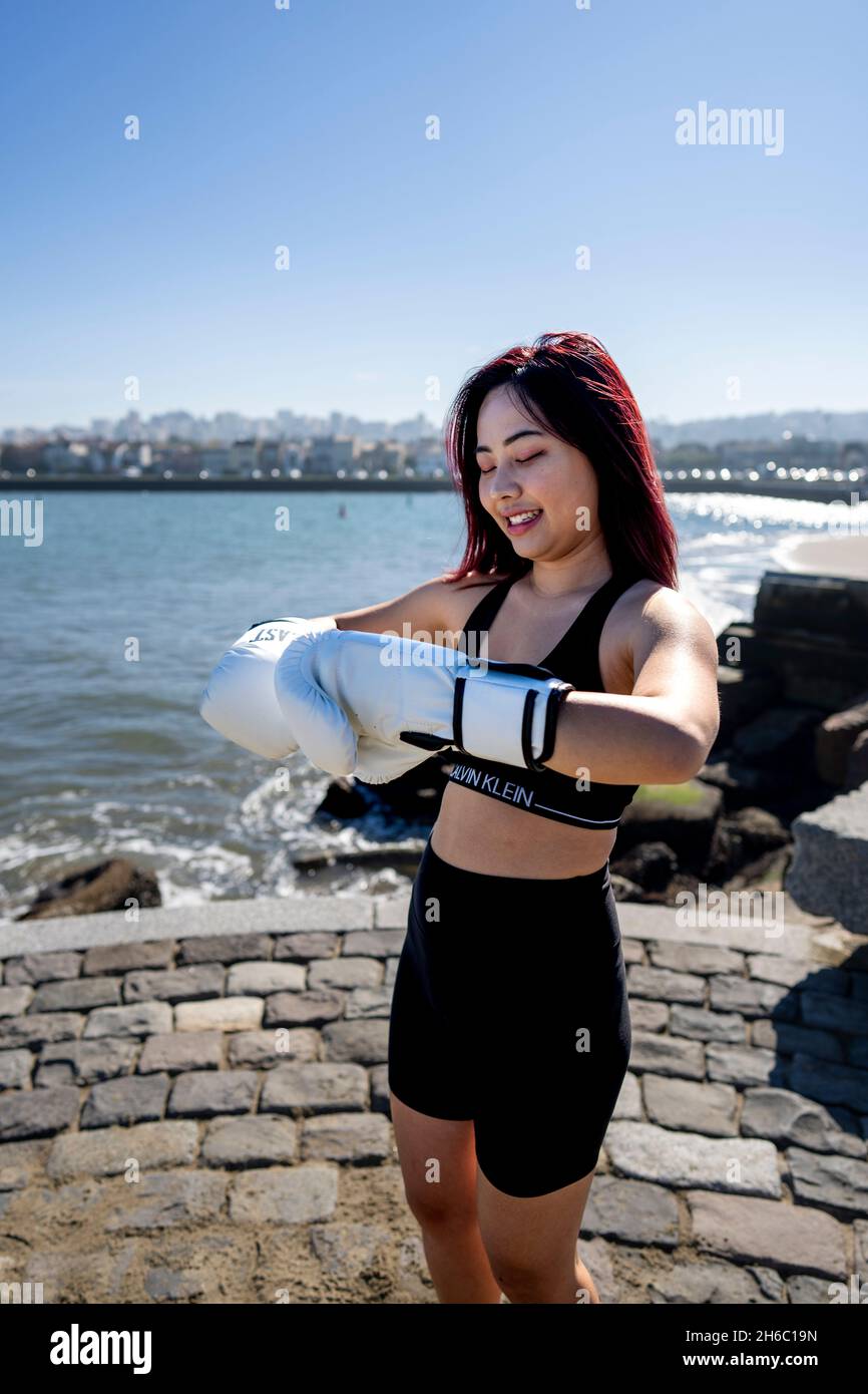 Junge asiatische Frau nimmt an der ersten MMA-Trainingseinheit mit Personal Trainer Teil Stockfoto