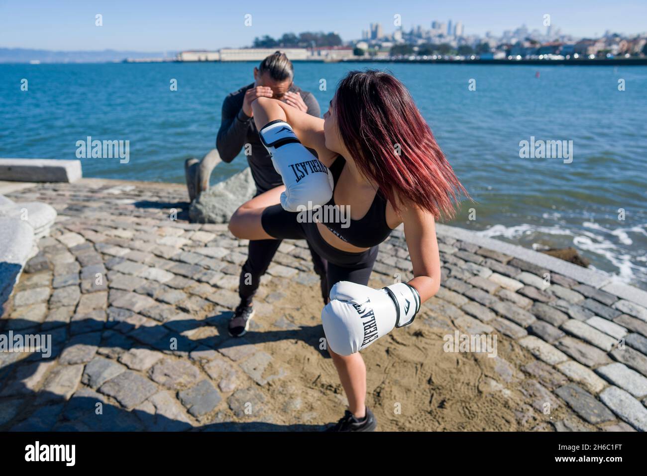 Junge asiatische Frau nimmt an der ersten MMA-Trainingseinheit mit Personal Trainer Teil Stockfoto