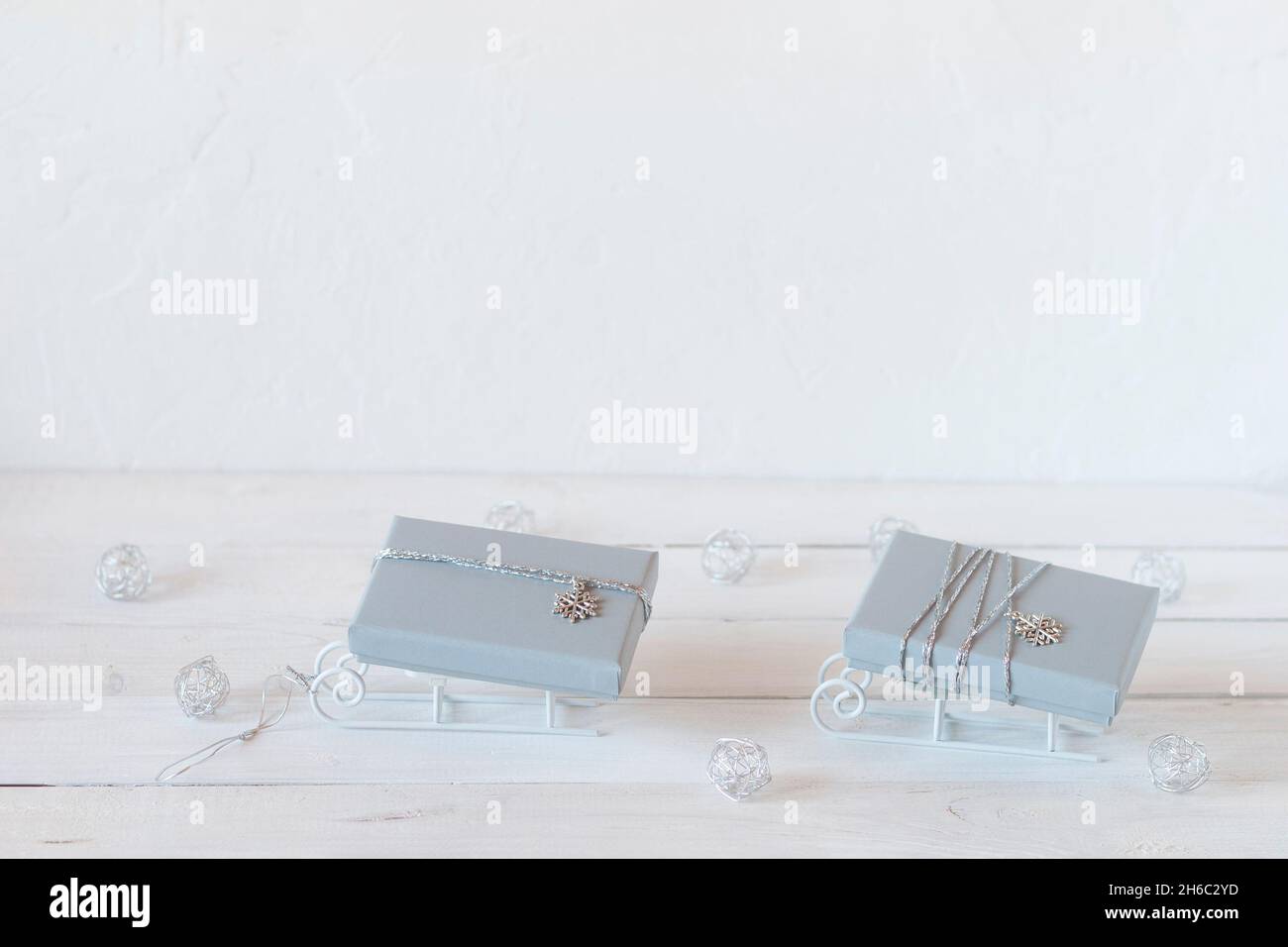 Kleine dekorative Schlitten mit grauen Weihnachts-Geschenkschachteln, weißen, grauen und silbernen Farben, Kopierraum, Idee für Weihnachtskarte Stockfoto