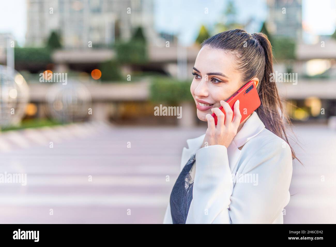 Weibliche Person lächelt, während sie am Telefon spricht Stockfoto