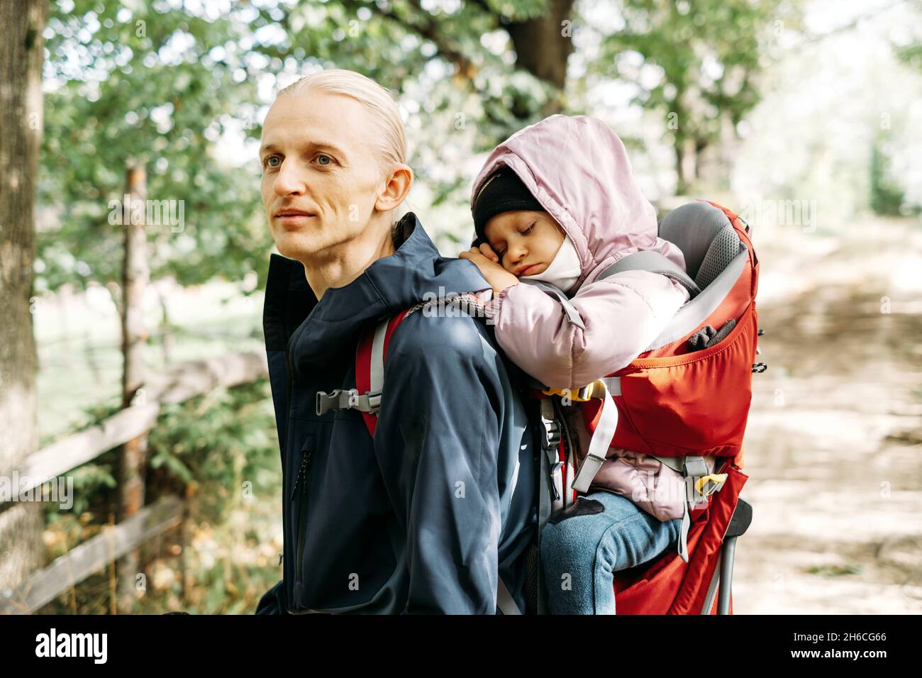 Müde, müde Kind, das mit dem Vater im Rucksack in den Bergen spazierengeht. Nordic Walk mit Familie und Kind im Herbst. Hindernisse und Herausforderungen für den Menschen Stockfoto