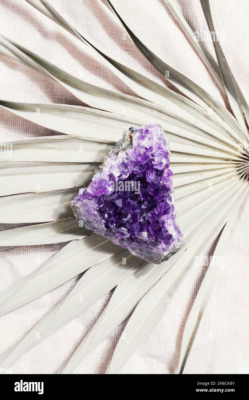 druse roher purpurner Amethyst-Kristall auf Palmblatt, magischer Fels für Ritual, Hexerei, spirituelle Praxis, meditation.esoteric Lebensbalance-Konzept. Stockfoto