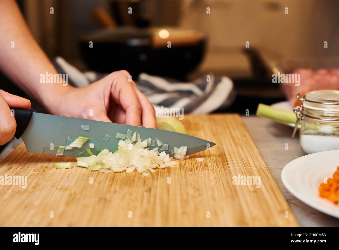 Frau mit Messer schneidet Zwiebel auf Scheiben zum Kochen Stockfoto