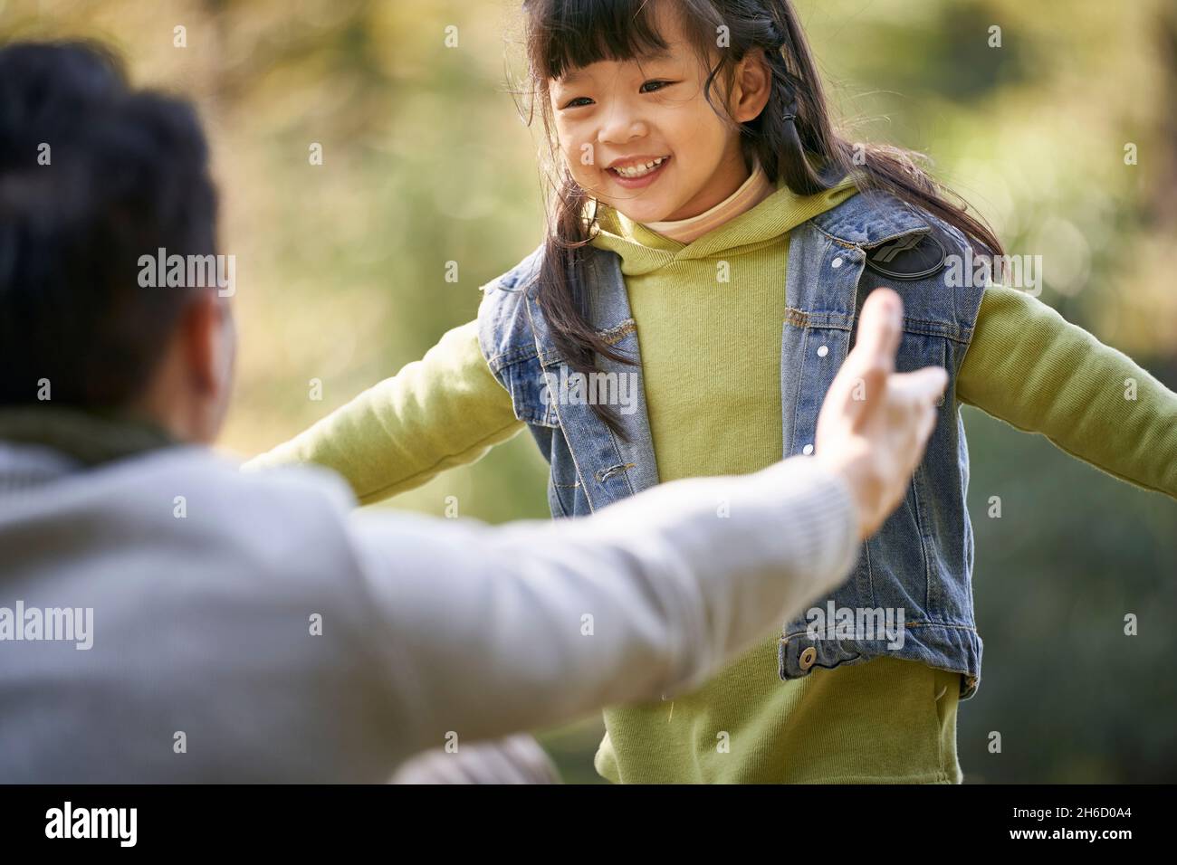 Junger asiatischer Vater umarmt 4-jährige Tochter im Freien in einem Park glücklich und lächelnd Stockfoto