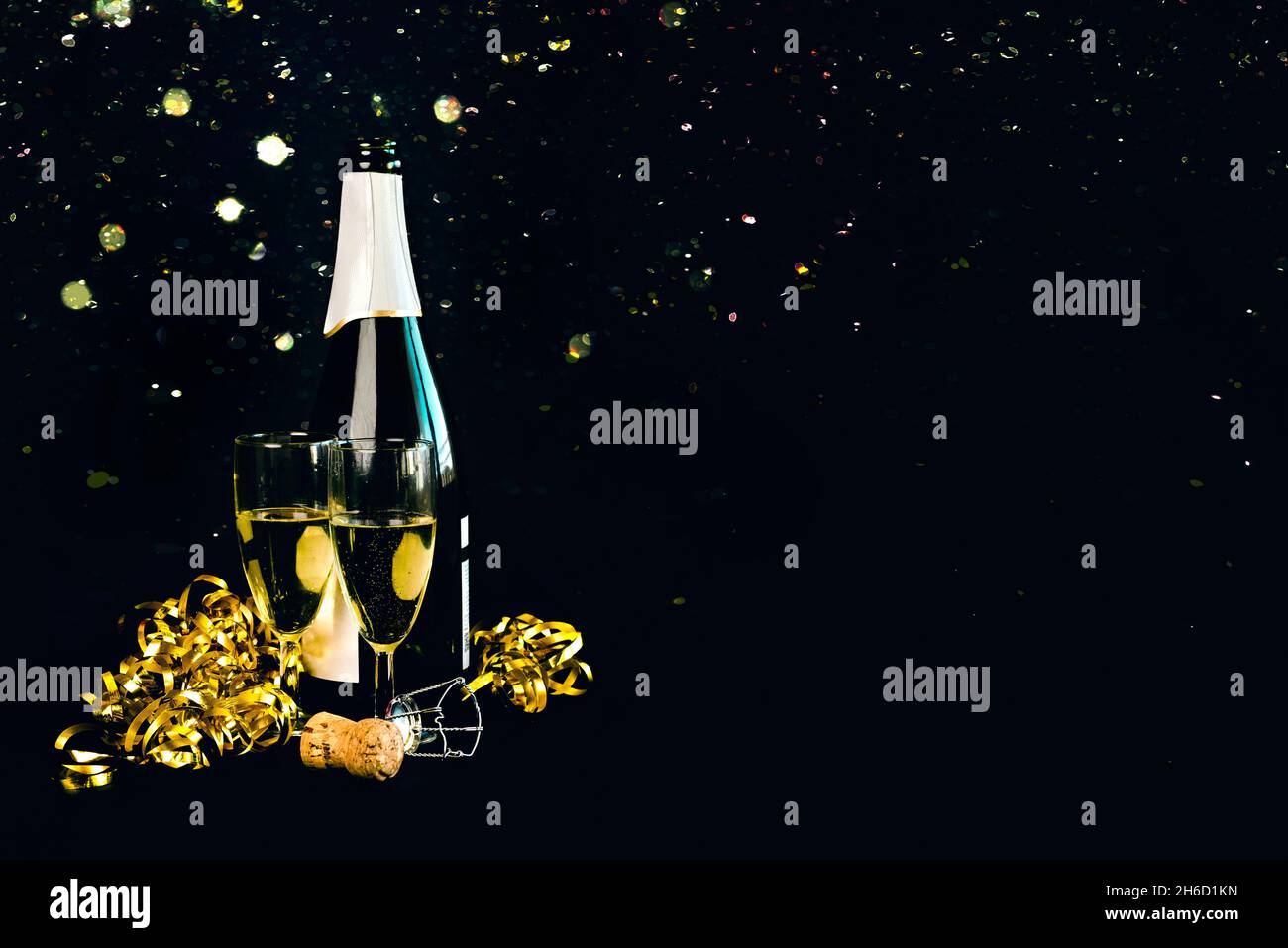 Frohes neues Jahr. Champagnerflasche mit zwei Gläsern, goldenen Luftschlangen und funkelndem Glitzer mit Platz für Text auf schwarzem Hintergrund. Silvesterabend Stockfoto