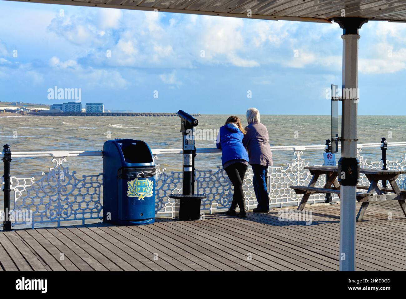 Rückansicht eines Paares am Palace Pier, das an einem sonnigen und windigen Herbsttag in Richtung Brighton Marina blickt Brighton East Sussex England Stockfoto