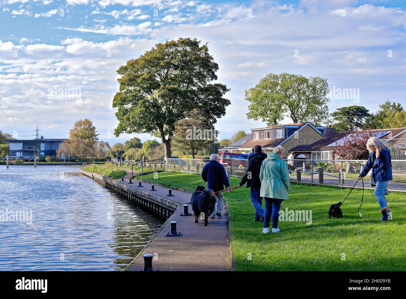 Eine gemischte Gruppe von Menschen, die an einem Herbsttag in Surrey England, England, mit ihren Haustieren an der Themse in Shepperton spazieren Stockfoto